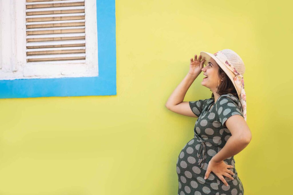 Happy pregnant woman in front of home window
