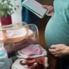 Pregnant woman at home preparing bag for newborn baby