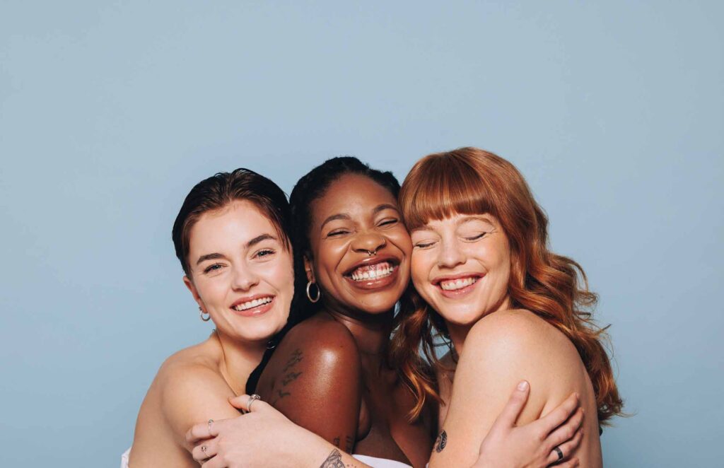 Group of happy women with different skin tones smiling and embracing each other