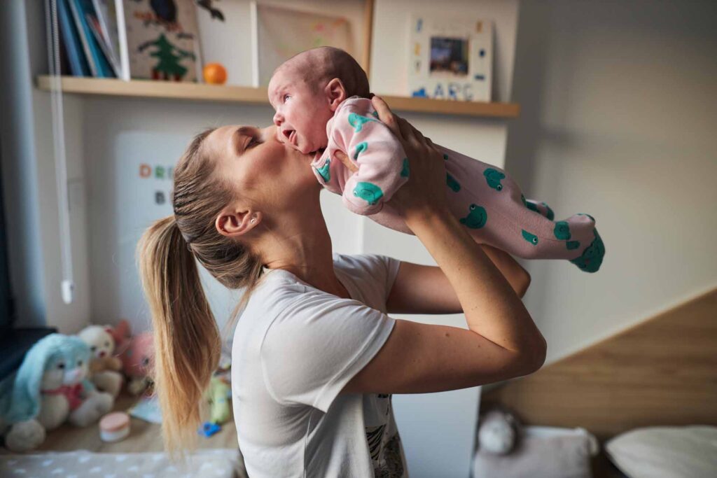 Mother holding up newborn baby and kissing them
