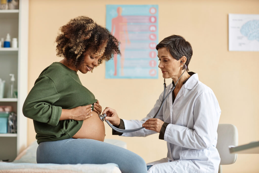 Pregnant black woman having check up from female doctor